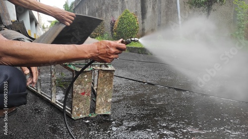 Close-up of a man's hand using a high-pressure water jet for contactless rug washing. Professional cleaning service in action, removing dirt from textile surfaces. For hygiene and service themes.