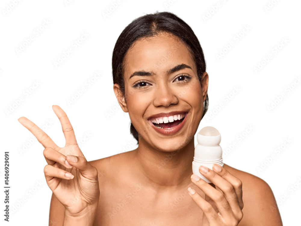 Filipino woman holds deodorant in studio joyful and carefree showing a peace symbol with fingers. Filipino woman holds deodorant in studio joyful and carefree showing a peace symbol with fingers.