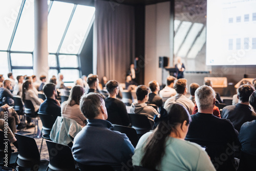 Female speaker giving a talk on corporate business conference. Unrecognizable people in audience at conference hall. Business and Entrepreneurship event
