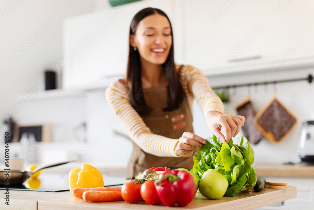Home made dinner preparation concept. Lady taking salad leaves while making healthy meal, selective focus on vegetables Home made dinner preparation concept. Lady taking salad leaves while making healthy meal, selective focus on vegetables
