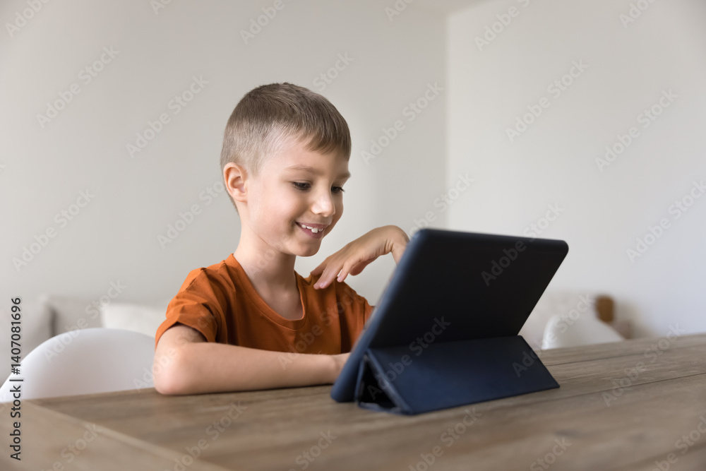 Interested in online learning. Curious smiling primary school age boy engaged in remote studying use digital tablet play interactive education game explore fun e-learning app enjoy virtual tour video Interested in online learning. Curious smiling primary school age boy engaged in remote studying use digital tablet play interactive education game explore fun e-learning app enjoy virtual tour video