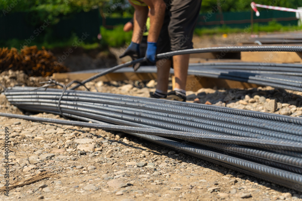 Construction worker bending steel reinforcement bars for foundation work, preparing the site for pouring concrete, ensuring structural integrity and longevity of the building