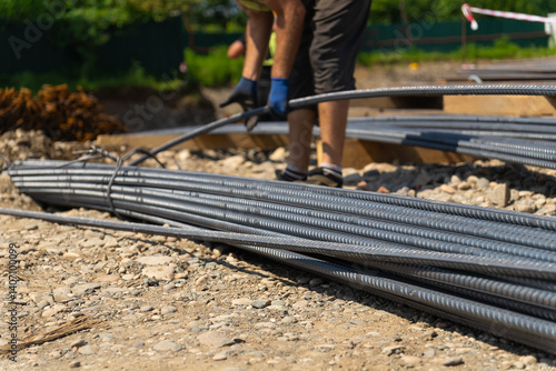 Obraz na płótnie Construction worker bending steel reinforcement bars for foundation work, preparing the site for pouring concrete, ensuring structural integrity and longevity of the building w salonie