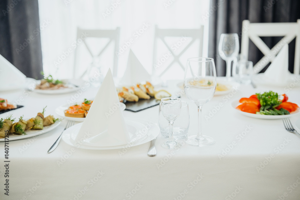Dining table arranged with various dishes and glassware in a bright setting Dining table arranged with various dishes and glassware in a bright setting