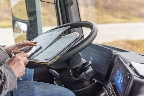Driver is checking work papers inside the truck All potential trademarks are  removed. Horizontally.