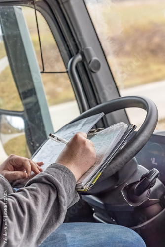 Driver is checking work papers inside the truck All potential trademarks are  removed. Vertical.