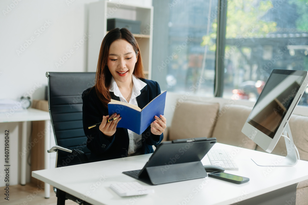 Young Asian businesswoman smiling and working with tablet and laptop in office. Young Asian businesswoman smiling and working with tablet and laptop in office.
