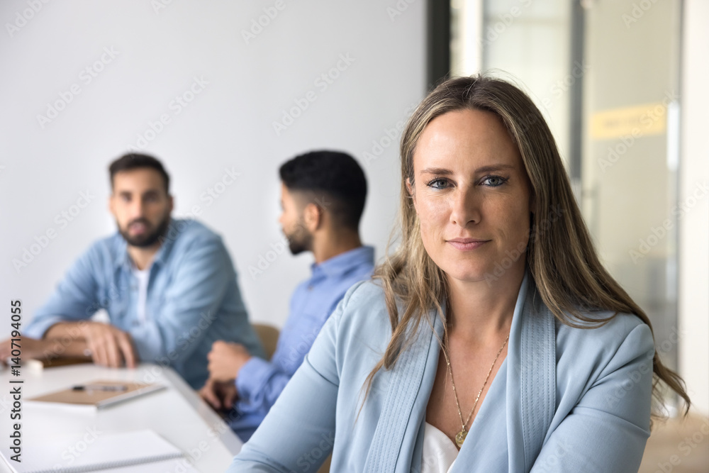 Confident professional. Portrait beautiful middle aged businesswoman international company worker employee posing at meeting table in modern office looking at camera taking break in collaborative work Confident professional. Portrait beautiful middle aged businesswoman international company worker employee posing at meeting table in modern office looking at camera taking break in collaborative work