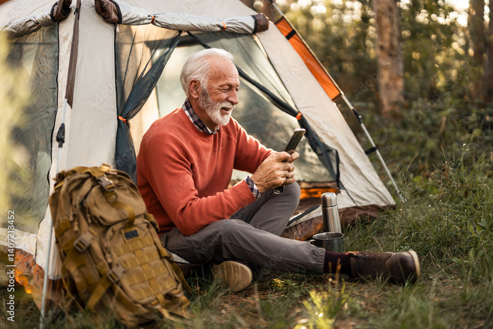Elderly Man Camping With Smartphone Beside Tent in Forest