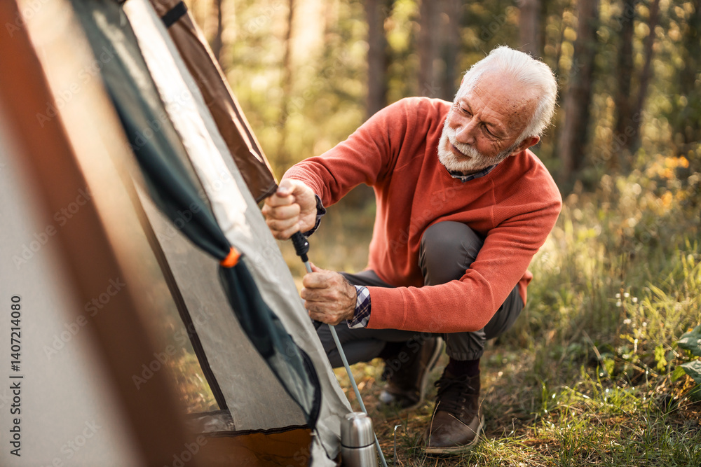Older Man Sets Up Tent in Forest During Camping Adventure