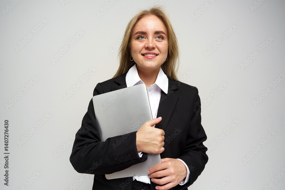Professional Woman in Business Attire Holds Laptop While Smiling Confidently in a Studio Setting Professional Woman in Business Attire Holds Laptop While Smiling Confidently in a Studio Setting