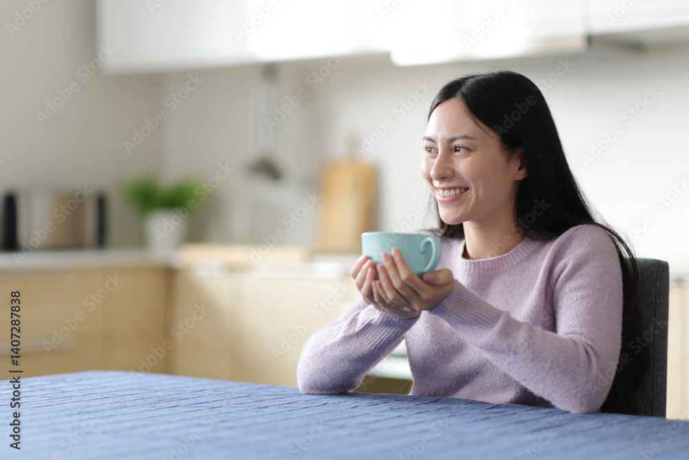 Asian woman drinking tea looking away at home Asian woman drinking tea looking away at home