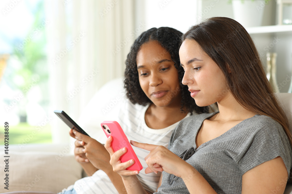 Interracial friends checking their phones in a house interior Interracial friends checking their phones in a house interior