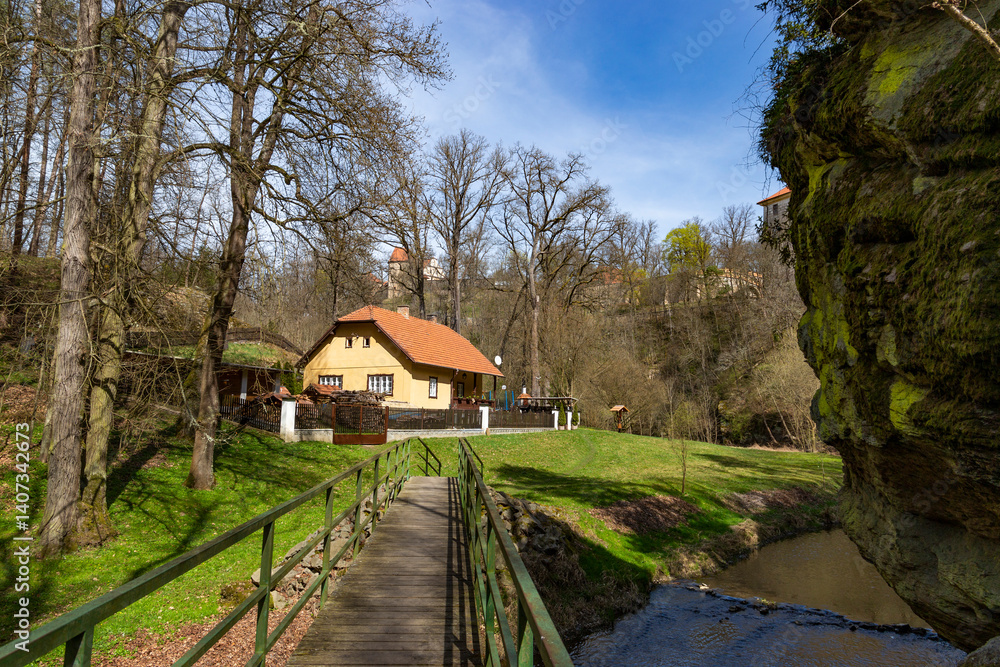 House by a stream near high cliffs. Warm spring day.