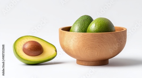 Obraz na płótnie Freshly Cut Avocado Halved and Placed on a Wooden Table Next to a Bowl of Whole Avocados w salonie