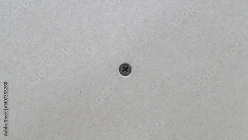 Black screw screwed into drywall close up