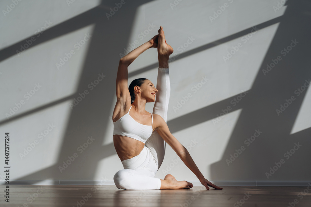 Fototapeta premium Model is doing yoga exercises. Beautiful young woman with slim body type is indoors