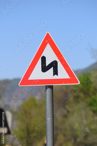in Pakistan , A traffic sign, warning of a double curve next to the road, Double Bend Ahead Road Sign