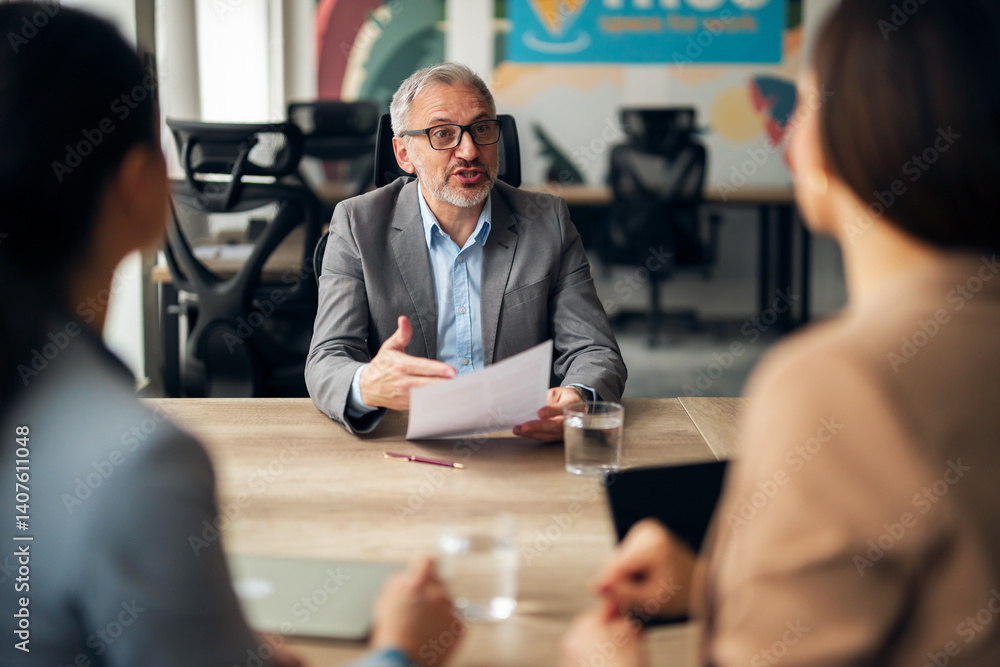 Senior Manager Discussing Business Strategies with Team Members in Modern Office