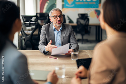 Obraz na płótnie Senior Manager Discussing Business Strategies with Team Members in Modern Office w salonie