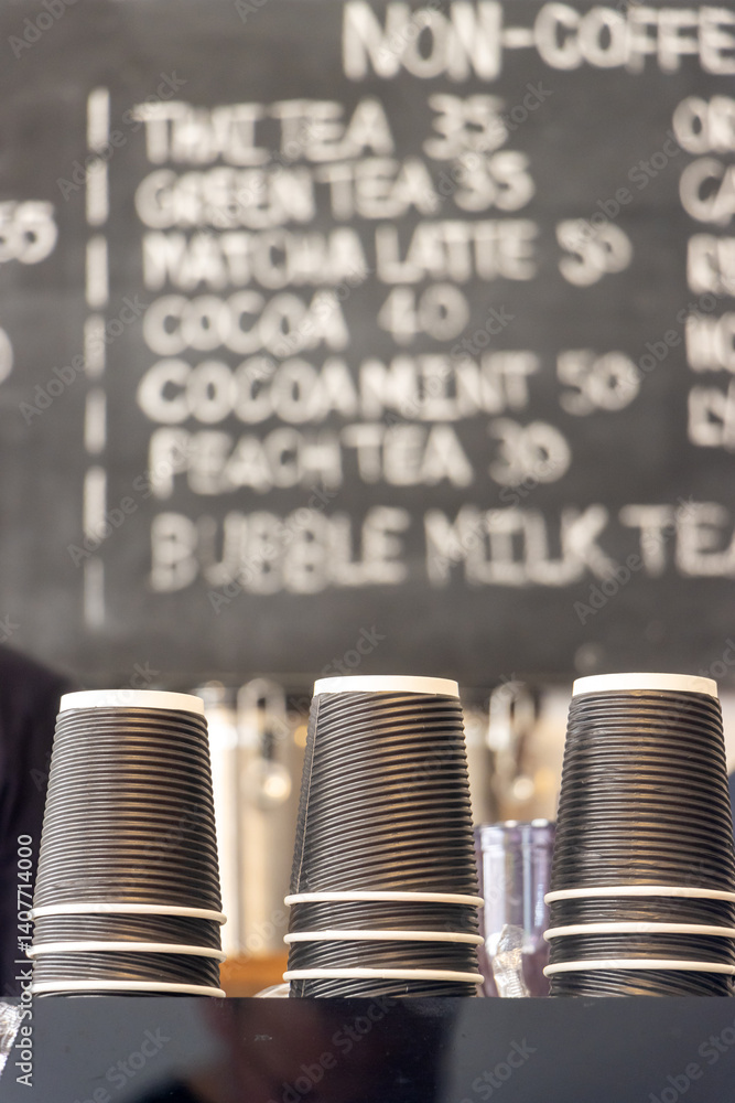 Disposable cups on a coffee shop counter with a daily menu in the background