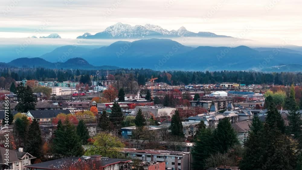 view of Coquitlam Mountain behind a cityscape with colorful trees on a cloudy autumn day in Canada view of Coquitlam Mountain behind a cityscape with colorful trees on a cloudy autumn day in Canada