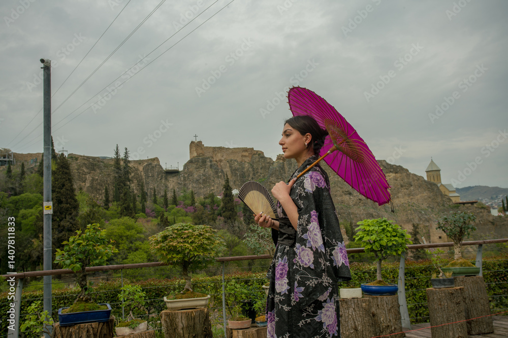 Beautiful young woman in Japanese kimono and close face with fan on holiday of cherry blossom