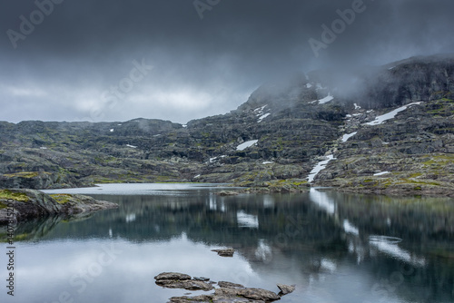 Reflection over a lake in moody vibe in the hike for Trolltunga,  Norway
