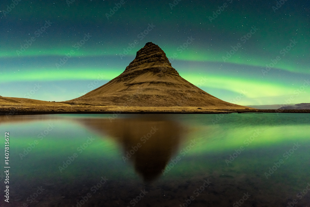 Spectacular reflection of the Kirkjufell mountain under the Northern Lights (Aurora Borealis) and starry sky in Iceland