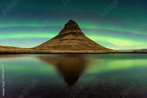 Spectacular reflection of the Kirkjufell mountain under the Northern Lights  (Aurora Borealis) and starry sky in Iceland