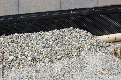 Tuyaux d'évacuation pluvial et eaux usées de la maison et membrane de fondation et soubassement avec alvéole et gravier de drainage