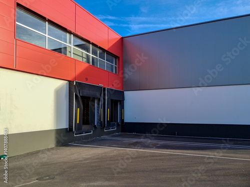 Empty loading docks of a distribution center with red and grey facade on a sunny day