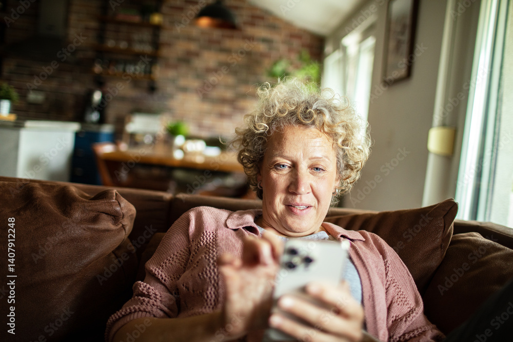 Senior woman using smartphone on the couch at home Senior woman using smartphone on the couch at home