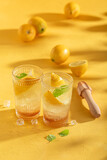 Fresh lemonade with ice on yellow wooden table.