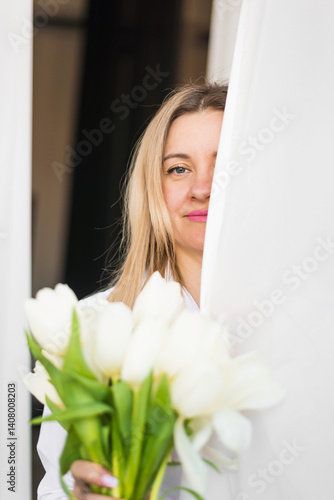 A woman holds white tulips in her hands