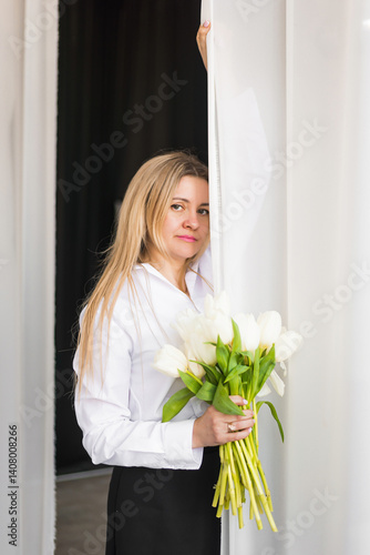 A woman holds white tulips in her hands