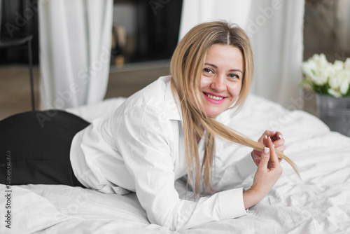 Young woman lying on white bed