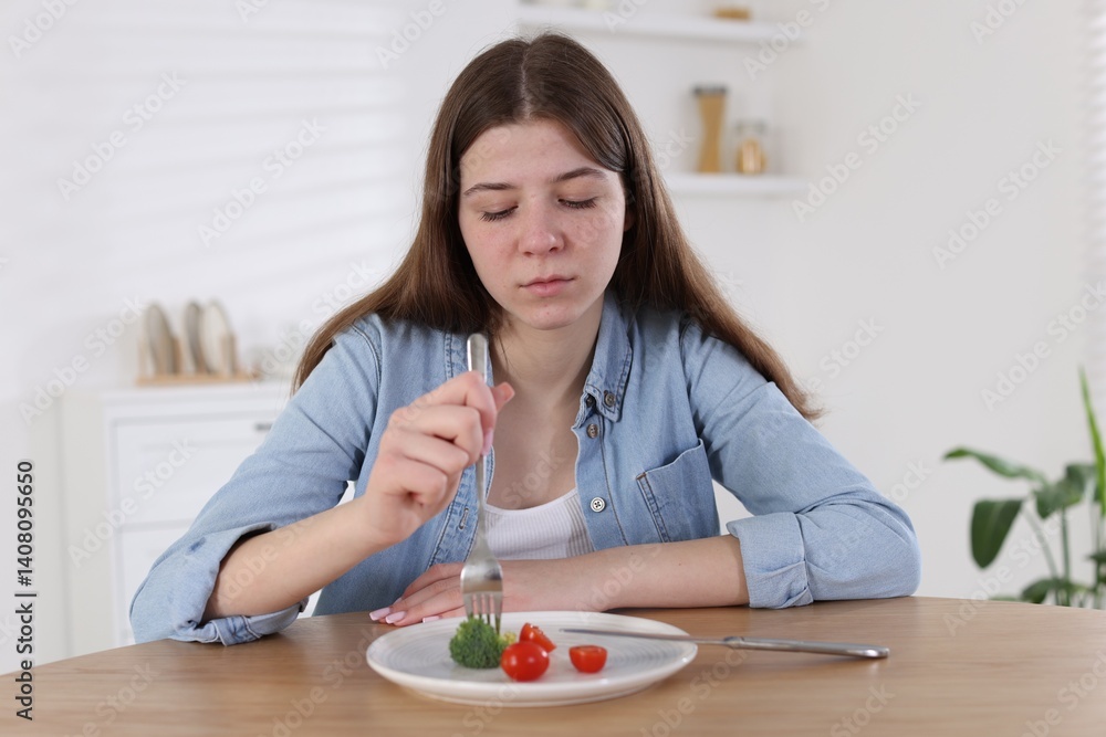 Sad teen girl holding fork with broccoli at home. Eating disorder Sad teen girl holding fork with broccoli at home. Eating disorder