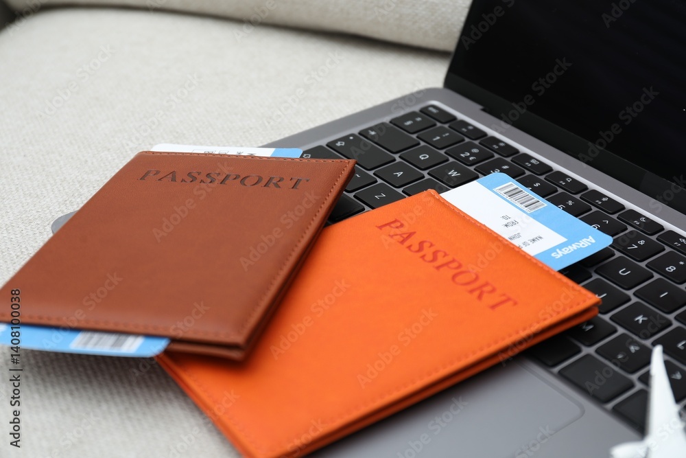 Passports, flight tickets and laptop on sofa, closeup