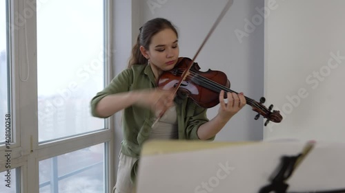 Focused young artist playing violin and studying music composition A dedicated violin student practices classical compositions, focusing on precision and technique