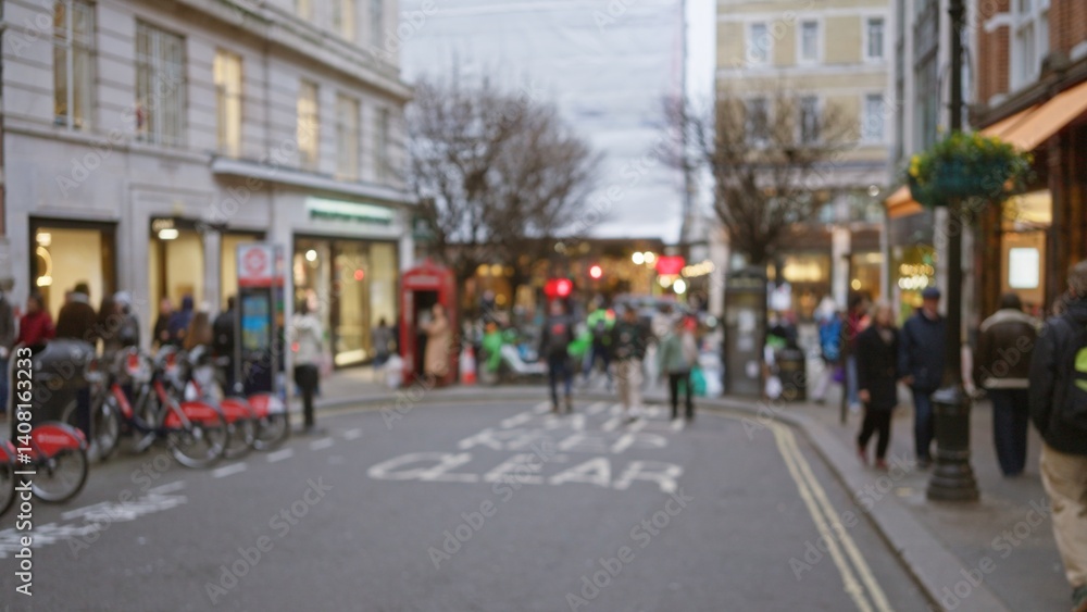 Blurry street scene with people in winter clothes walking past shops and red phone boxes in london, uk, showcasing the lively atmosphere of a bustling city.