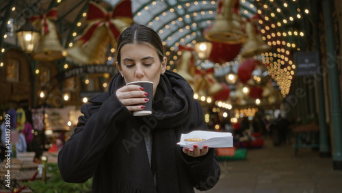 Photography Woman enjoying hot drink in festive covent garden surrounded by christmas lights, capturing a joyful moment on a london street during winter holidays