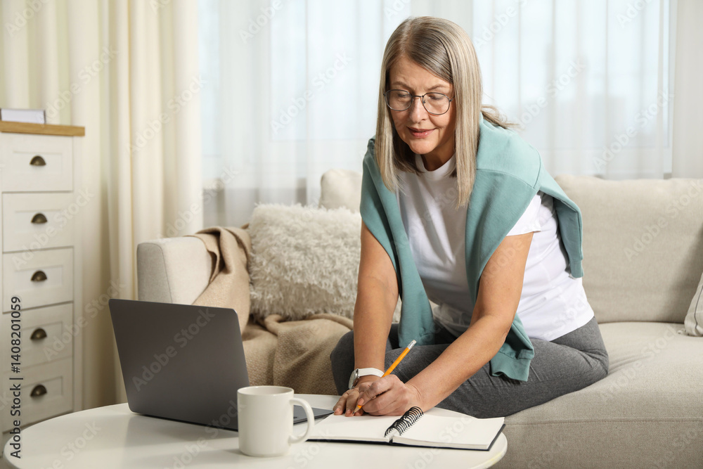 Woman learning online using laptop and taking notes at table indoors. Self-study Woman learning online using laptop and taking notes at table indoors. Self-study