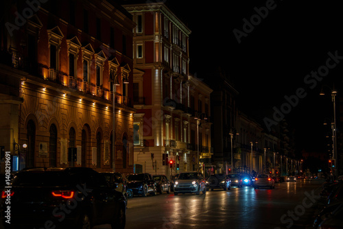 Fototapeta Naklejka Na Ścianę i Meble -  Bari city night street with illuminated landmark buildings and glowing streetlights in Puglia (Apulia), Italy—showcasing historic charm and urban elegance.