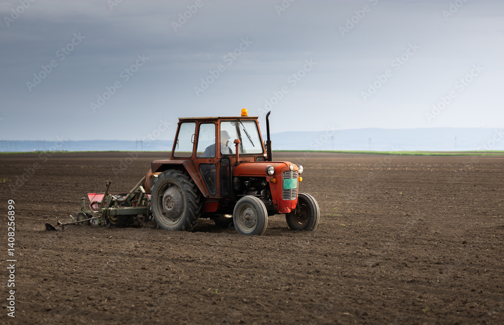 Fototapeta premium Farmer with tractor seeding in sunset