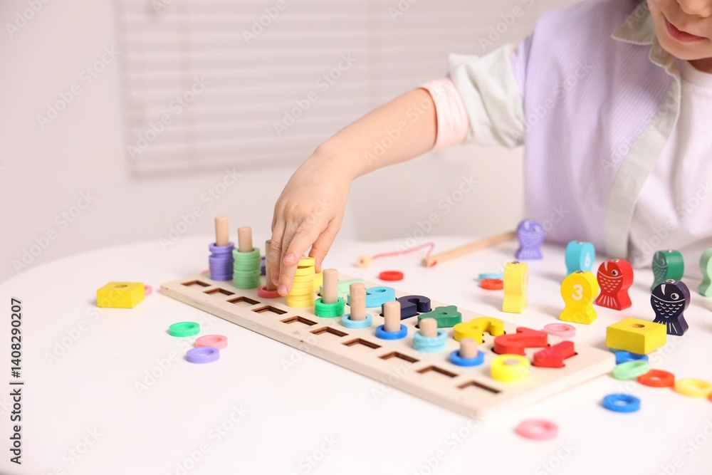 Motor skills development. Little girl playing with math game Fishing for Numbers at white table indoors, closeup Motor skills development. Little girl playing with math game Fishing for Numbers at white table indoors, closeup