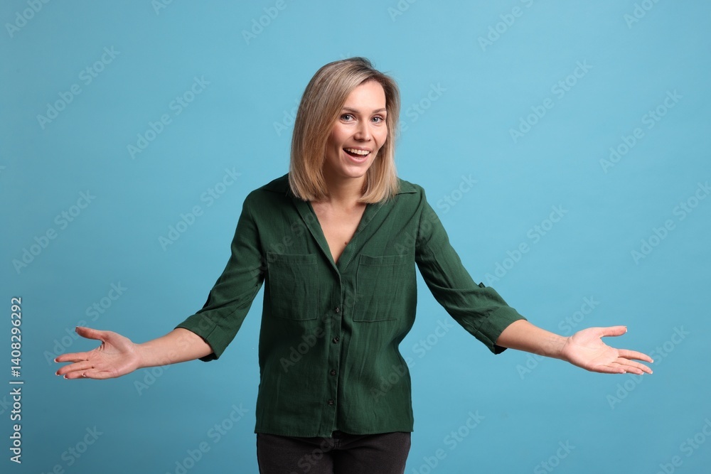 Cheerful woman welcoming guests on light blue background