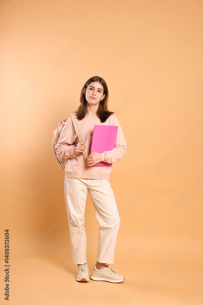 Teenage girl with backpack and folder on beige background Teenage girl with backpack and folder on beige background
