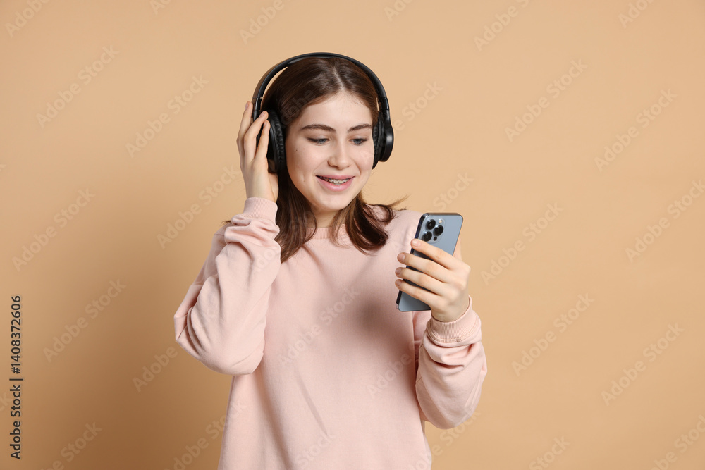 Portrait of teenage girl in headphones with smartphone on beige background Portrait of teenage girl in headphones with smartphone on beige background