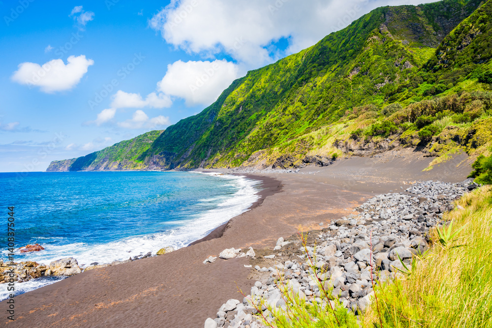 Black sand volcanic beach of Faja and green tropical landscape with high cliffs on ocean coast, Faial island, Azores, Portugal